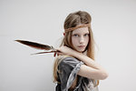 Portrait of girl wearing leather braid around head, holding feather