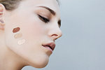 Studio head shot of young woman with palette of foundation makeup on skin