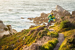 Mountain biker riding up coastal path, Monterey Bay area, California, USA