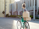 Young woman pushing bicycle with cardboard boxes
