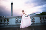 Portrait of young woman in evening gown at dusk, Trafalgar Square, London, UK
