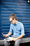 Young man looking at print outs of designs outside