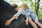 Cropped shot of two brother riding on horse