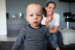 Portrait of baby boy in front of mother in living room