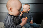 Baby twin brothers eating biscuits in living room