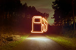 Glowing gas pump symbol above forest road at night