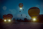 Illuminated hot air balloons rising toward sky at night, Cappadocia, Anatolia,Turkey