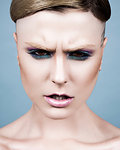 Young woman with short hairstyle, dark eye make-up and angry expression