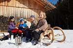 Children having break of pretzels and warm drink in snow