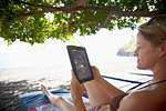 Woman using digital tablet on beach, Amed, Jemeluk beach, Bali, Indonesia
