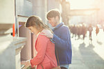 Couple withdrawing money from cash machine on street, London, UK