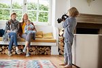 Boy taking photograph of adult women and boy sitting in window seat