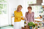 Woman opening wine bottle in kitchen