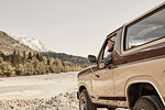 Mid adult man in pickup truck, leaning out of window looking at mountain range, Wallgau, Bavaria, germany