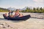 Family using paddles to steer dinghy on water, Wallgau, Bavaria, germany