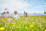 Young boy running through field, mother, father and brother following behind, next to solar farm