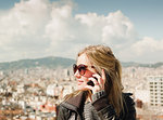Female tourist ltalking on smartphone in front of cityscape from Montjuic Hill, Barcelona, Spain
