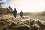 Rear view of mother and son running on grassland