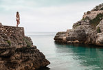 Rear view of young woman in bikini looking out from Cala en Brut, Menorca, Balearic islands, Spain