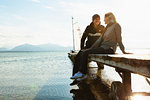 Mature couple sitting on jetty, smiling