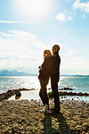 Mature couple standing beside lake, hugging, looking at view