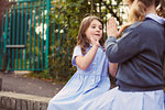 Elementary schoolgirls playing hand clapping game in school playground