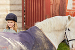 Girl and pony looking over their shoulder at stable