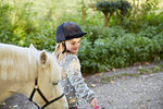 Girl leading white pony on rural road