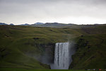Waterfall flowing from lush green cliffs, Iceland