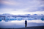 Rear view of mid adult woman in silhouette by Jokulsarlon glacial lake, Iceland