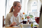 Mid adult woman having lunch with friend in cafe