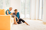 Two mature women taking an exercise break on living room sofa