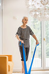 Senior woman exercising in living room pulling resistance band