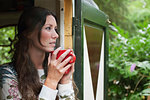 Young woman drinking coffee in cabin doorway