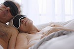 Senior couple sleeping in face masks in bed