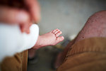 Father holding newborn baby boy's foot