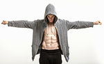 Body builder in hoodie with outstretched arms exposing abdominal muscle
