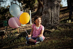 Girl on grass holding balloons