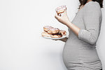 Pregnant woman holding plate of doughnuts