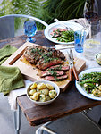 Dinner table with barbecued herb crust lamb and spring greens