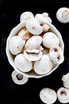 Bowl of white mushrooms on black background