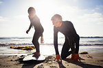 Father and son practicing with surfboard on beach, Encinitas, California, USA