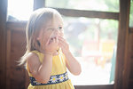 Close up of female toddler with hands over mouth