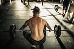 Mid adult man preparing to lift barbell in gymnasium