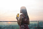 Woman with drink against cityscape, Bangkok, Thailand