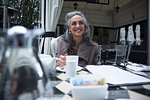 Mature woman having coffee break on luxury porch