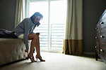 Mature woman sitting on bed putting on high heels