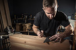 Male carpenter measuring wooden plank with set square in workshop