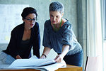 Two businesswomen checking blue prints in office