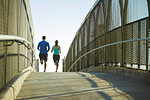 Man and woman running over bridge